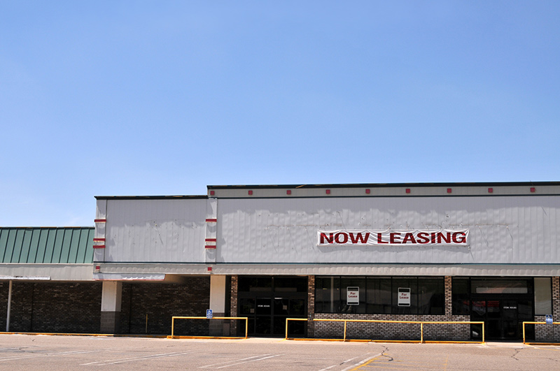 Vacant commercial building with "Now Leasing" sign 